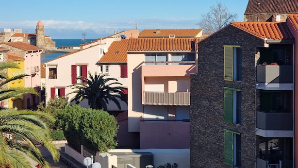 Eine Küstenstadt mit bunten Häusern, einem markanten Steinbauwerk und Blick auf das Meer.