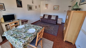Ein gemütlicher Wohnbereich mit Esstisch, Sofa und Fernseher.