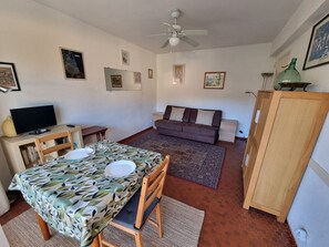 A compact living space with a dining table, sofa, and television. - Studio with terrace - 2 guests (Collioure)