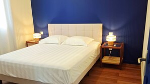 A bed with a headboard, two bedside tables with lamps, and wooden flooring. - House with private pool - 4 guests (Saint-Joseph)