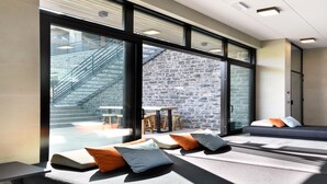 Un espacio lounge moderno con grandes ventanales, una pared de piedra y asientos con cojines.