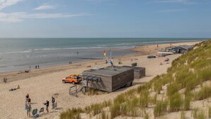 A beach with a lifeguard tower, a lifeguard station, and a dune buggy. - Duinhoeve chalet Schelp (Burgh-Haamstede)