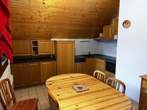 Eine Holzküche mit einem runden Esstisch und Stühlen, einem Herd und einer Spüle.