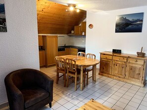 Eine gemütliche Küche mit Holzschränken, einem Esstisch mit Stühlen und einem schwarzen Ledersofa.