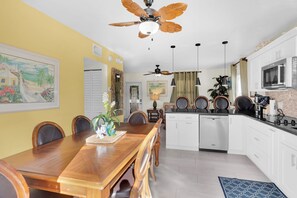 Eine moderne Küche mit weißen Schränken, einem Holzespeisetisch und einem Deckenventilator.
