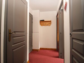 A hallway with closed doors, a wooden coat rack, and a red carpet. - Apartment with parking - 6 guests (Valloire)