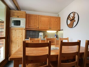 A wooden kitchen with cabinets, a microwave, and a dining table with chairs. - Apartment with parking - 6 guests (Valloire)