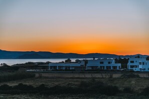 A coastal landscape with modern white buildings, a body of water, and distant mountains. - Naxos Cube Villa / Panoramic View Maisonette (Plaka)