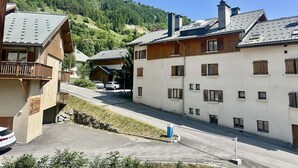 A mountain village with traditional wooden buildings, a clear road, and a parking area. - Family apartment - 6 guests (Valloire)