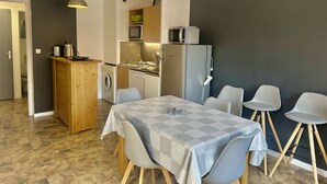 A compact kitchen with a microwave, sink, and refrigerator, a dining area with a table and chairs, and a wooden cabinet. - Family apartment - 6 guests (Valloire)