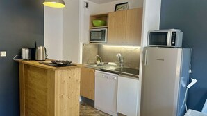 A compact kitchen with a wooden island, a sink, a dishwasher, a microwave, and a refrigerator. - Family apartment - 6 guests (Valloire)