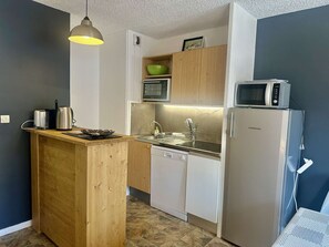 A compact kitchen with a wooden island, a sink, a dishwasher, a microwave, and a refrigerator. - Family apartment - 6 guests (Valloire)
