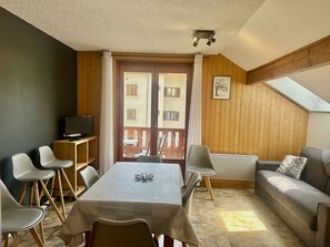A cozy room with a dining table, chairs, a sofa, and a TV. - Family apartment - 6 guests (Valloire)