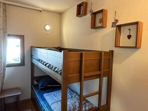 A bunk bed room with a window, a small stool, and wall decorations including a heart and a moose.