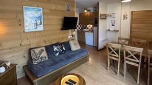 A cozy living area with a sofa, a television, and a wooden wall. - Cozy apartment, parking, pets welcome - 6 guests (Valloire)