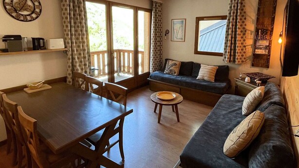 A living room with a dining table, sofa, and a large window with curtains. - Cozy apartment, parking, pets welcome - 6 guests (Valloire)