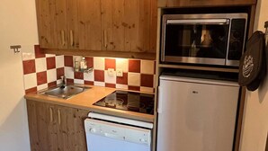 A compact kitchen with wooden cabinets, a microwave, a dishwasher, and a checkered backsplash. - Cozy apartment, parking, pets welcome - 6 guests (Valloire)