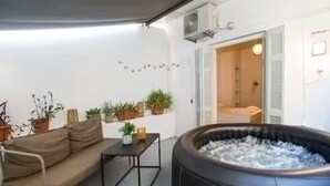 A cozy outdoor seating area with a sofa and a table, surrounded by potted plants. - Athens Central Jacuzzi Retreat (Athens)