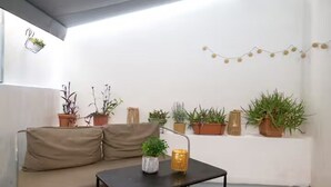 A cozy corner with a beige sofa, a small black table, and various potted plants. - Athens Central Jacuzzi Retreat (Athens)