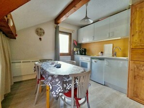 A compact kitchen with a dining table, chairs, a refrigerator, and a window. - Central studio - 4 guests (Valloire)