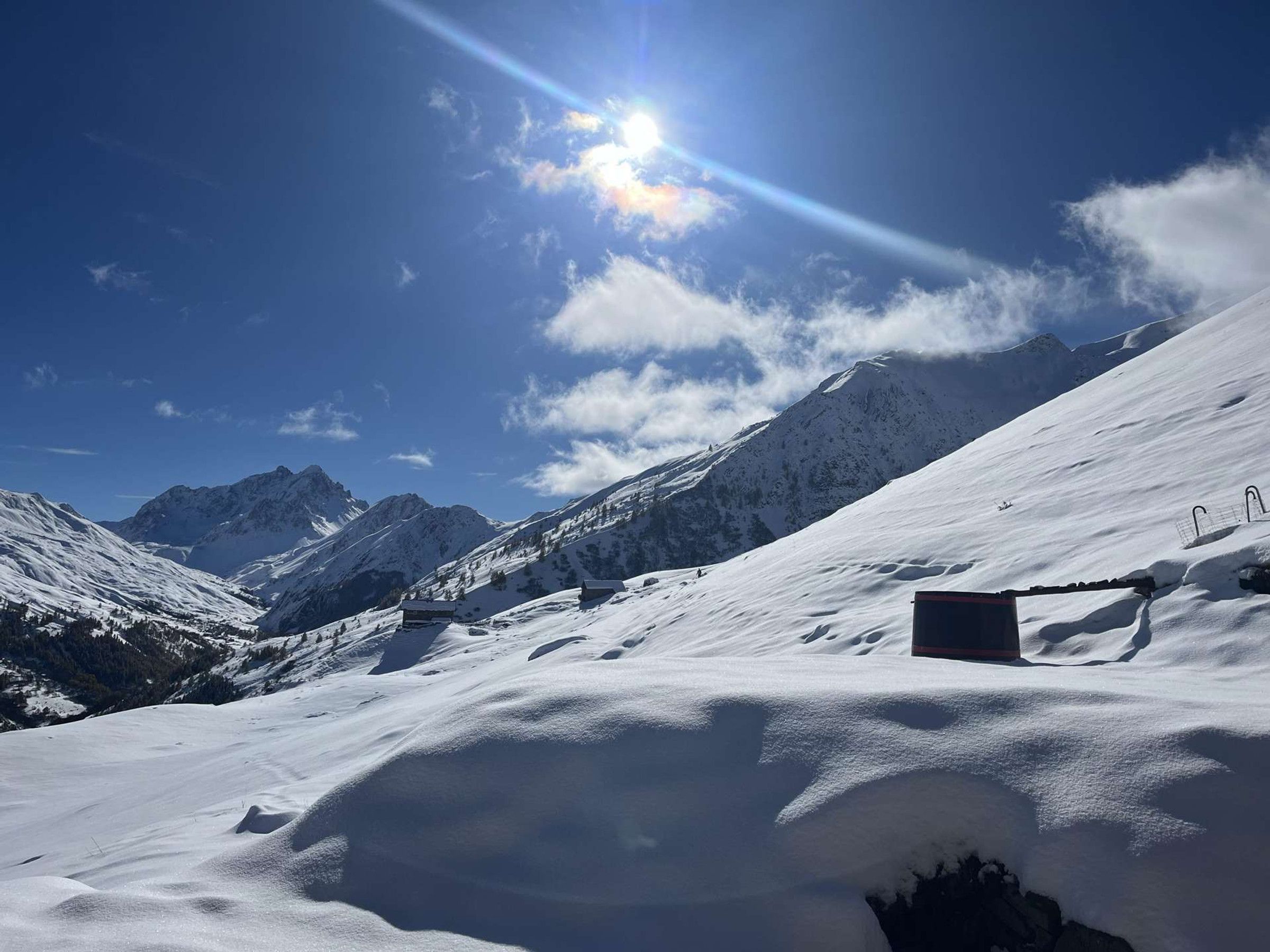 Et sneklædt bjerglandskab med klar himmel og stærk sol.