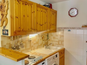 A kitchen with wooden cabinets, a sink, a stove, and a washing machine. - Cozy central apartment - 5 guests (Valloire)