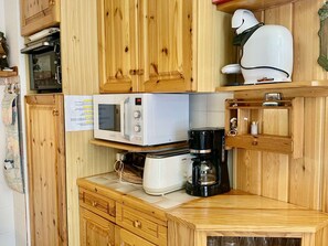 A compact kitchen with wooden cabinets, a microwave, a coffee maker, and a small refrigerator. - Cozy central apartment - 5 guests (Valloire)
