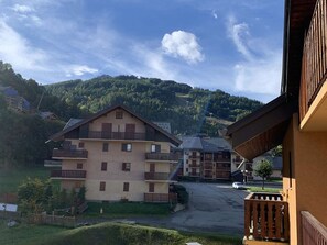 A multi-story hotel with balconies, set against a backdrop of a mountainous landscape. - Functional studio with cabin - 4 guests (Valloire)