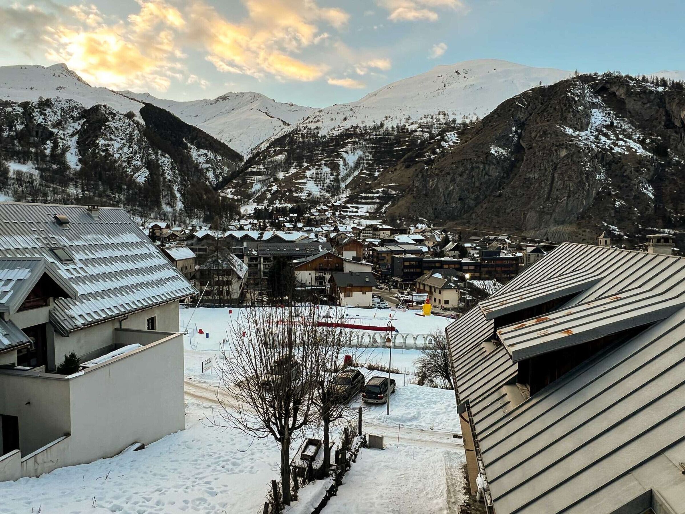A snow-covered village with buildings and mountains in the background.