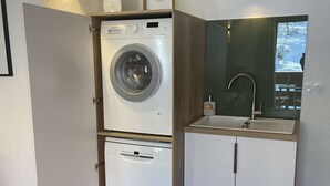 Ett kompakt tvättrum med en tvättmaskin och en diskmaskin från Bosch, ett litet handfat och en spegel ovanför handfatet.