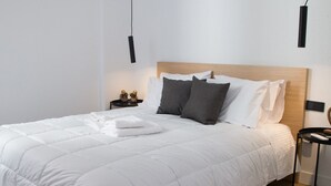 Un lit bien fait, avec une tête de lit en bois, une table de chevet avec une lampe et un luminaire fixé au mur.