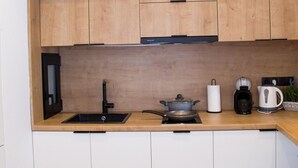 Une cuisine moderne avec des meubles blancs, un plan de travail en bois, un évier, une cuisinière et une machine à café.