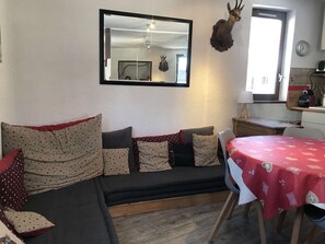Ein gemütlicher Wohnbereich mit einer Couch, einem Esstisch und einem Spiegel.