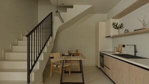 Une cuisine moderne avec un coin repas, comprenant un escalier, des meubles en bois et un design minimaliste.
