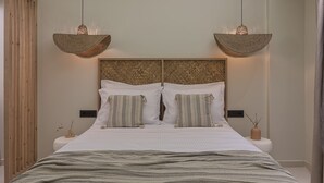 Une chambre à coucher comprenant un lit, deux tables de chevet, une tête de lit et deux luminaires suspendus.
