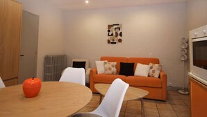 Ein modernes Wohnzimmer mit Holztisch, orangefarbenem Sofa und weißen Sesseln.