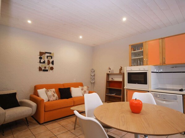A compact living space with a sofa, a dining table, and a kitchen area including a stove and oven. - Central apartment, pets welcome - 4 guests (Valloire)
