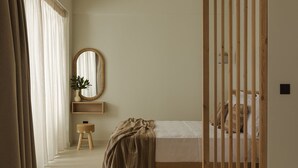 A bedroom with a bed, a bedside table, a mirror, and a window with curtains. - Luxury Suite with Private Pool by Kiva (Mitikas)