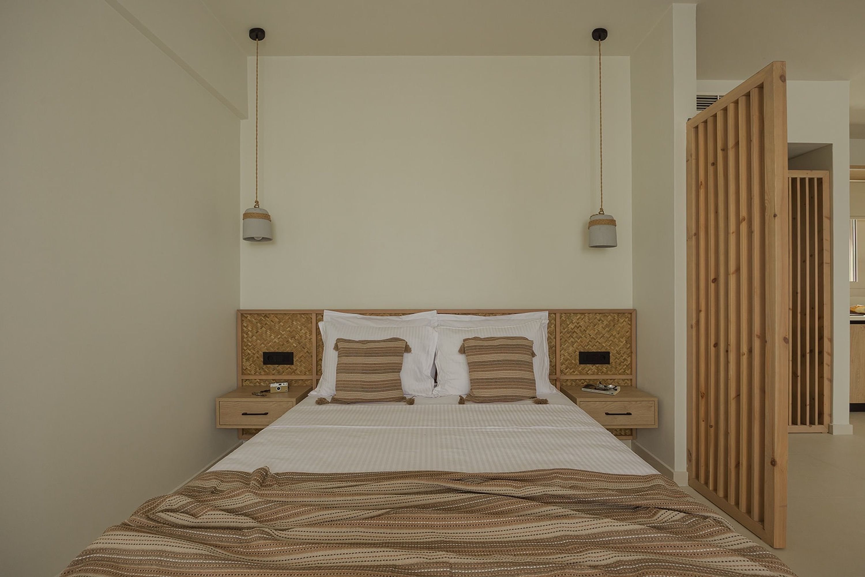 A bed with a striped bedspread, two bedside tables with lamps, and a wooden partition.