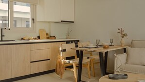 A modern kitchen with wooden cabinets, a dining area with a round table, and a sofa. - Luxury Suite with Private Pool by Kiva (Mitikas)