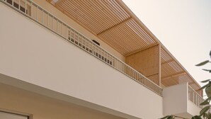 Ein modernes, zweistöckiges Haus mit Schwimmbad, Sitzgelegenheit im Freien und einem Balkon.