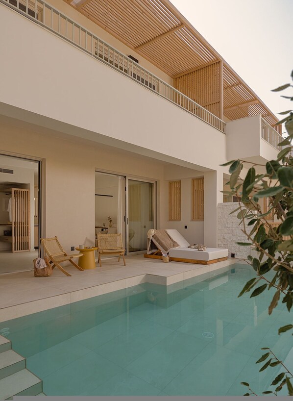 Ein modernes, zweistöckiges Haus mit Schwimmbad, Sitzgelegenheit im Freien und einem Balkon.