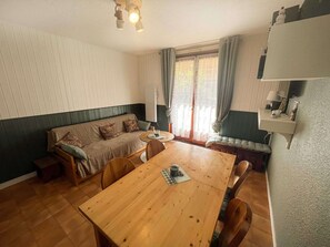 A cozy room with a wooden dining table, a sofa, and a bench. - Cozy apartment - 4 guests (Valloire)