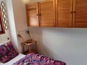 A bedroom with a bed, a desk with a chair, and wooden cabinets above the bed. - Cozy apartment - 4 guests (Valloire)