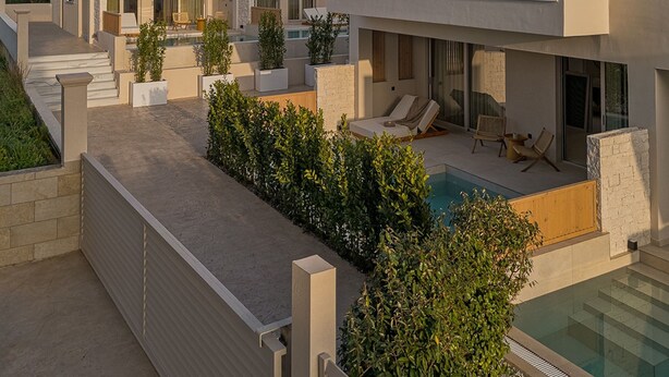 A modern multi-story residential building with a pool, outdoor seating, and a well-maintained garden. - Luxury Suite with Balcony by Kiva (Mitikas)