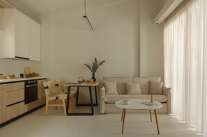 Eine moderne Küche mit Holzausstattung, einem Esstisch mit Stühlen, einer Couch und einem kleinen Tisch mit einer Vase.