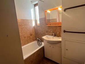 A bathroom with a bathtub, a sink, and a mirror. - Practical studio cabin - 4 guests (Valloire)