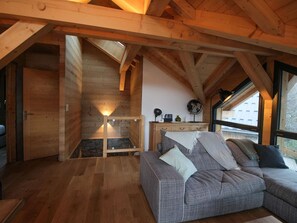 A wooden interior with a sofa, a small table, and a window. - Exceptional chalet with Galibier view - 10 guests (Valloire)