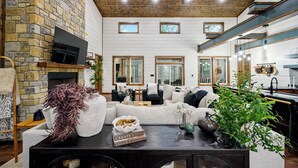 Una amplia sala de estar con chimenea de piedra, un sofá grande y un comedor con mesa de madera.