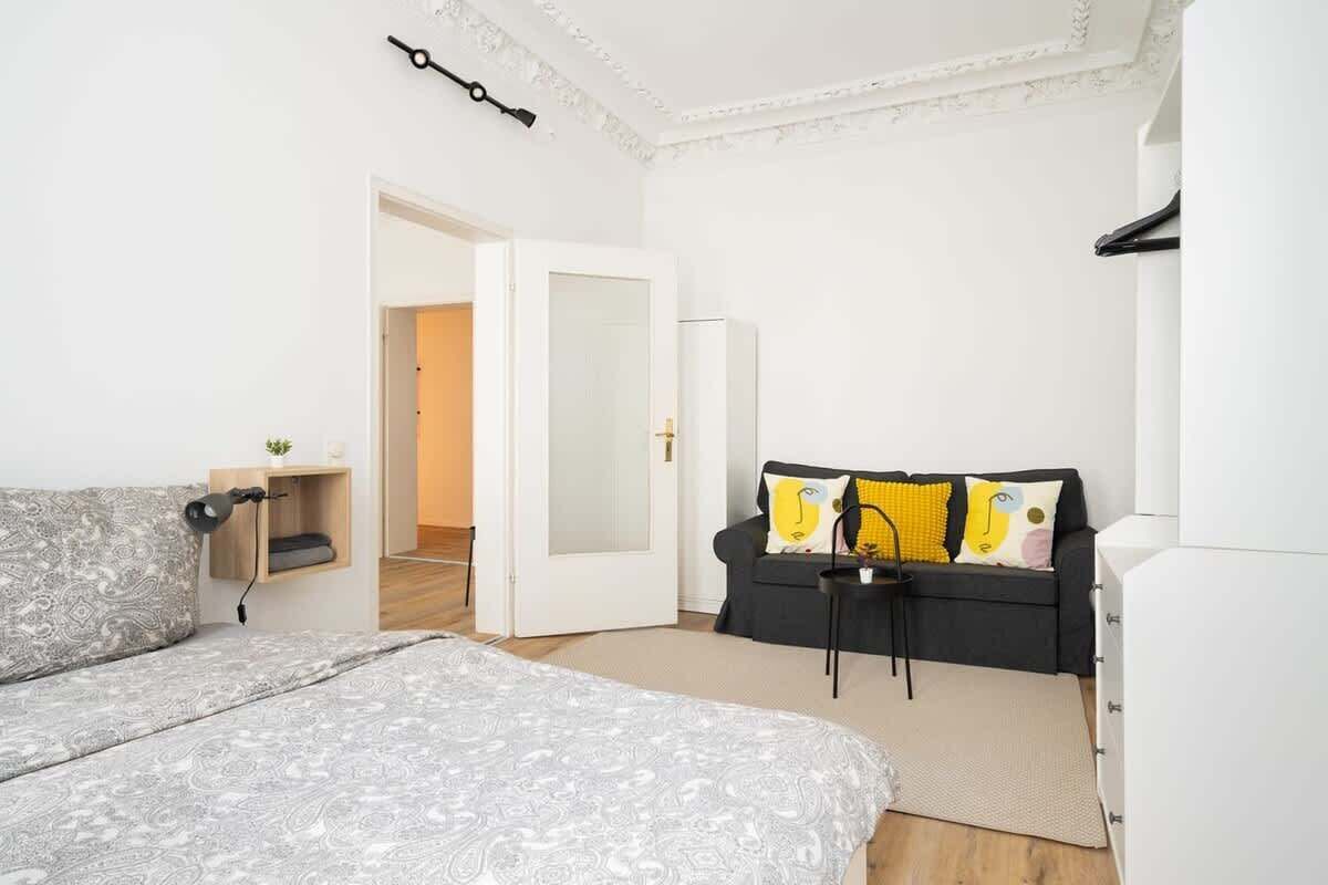 A modern bedroom with a bed, a sofa, a small table, and a wardrobe.